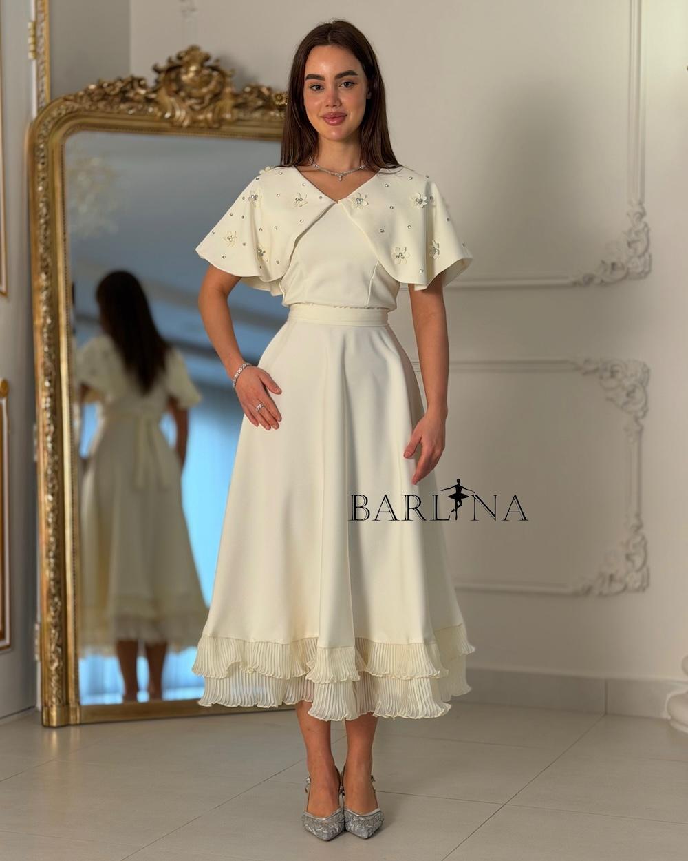 Dress with embroidered cape and pleats at the bottom
