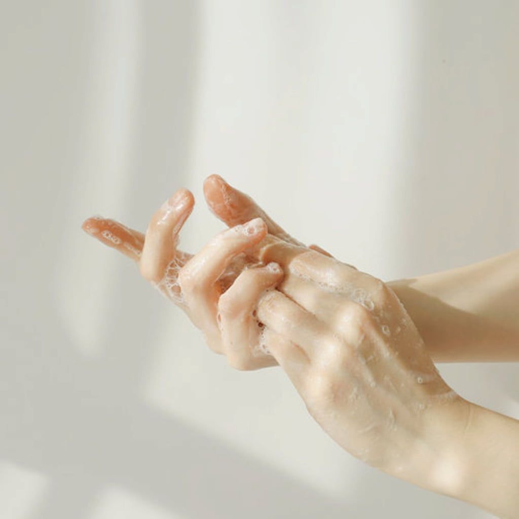 A hand applying a green cream onto the hand