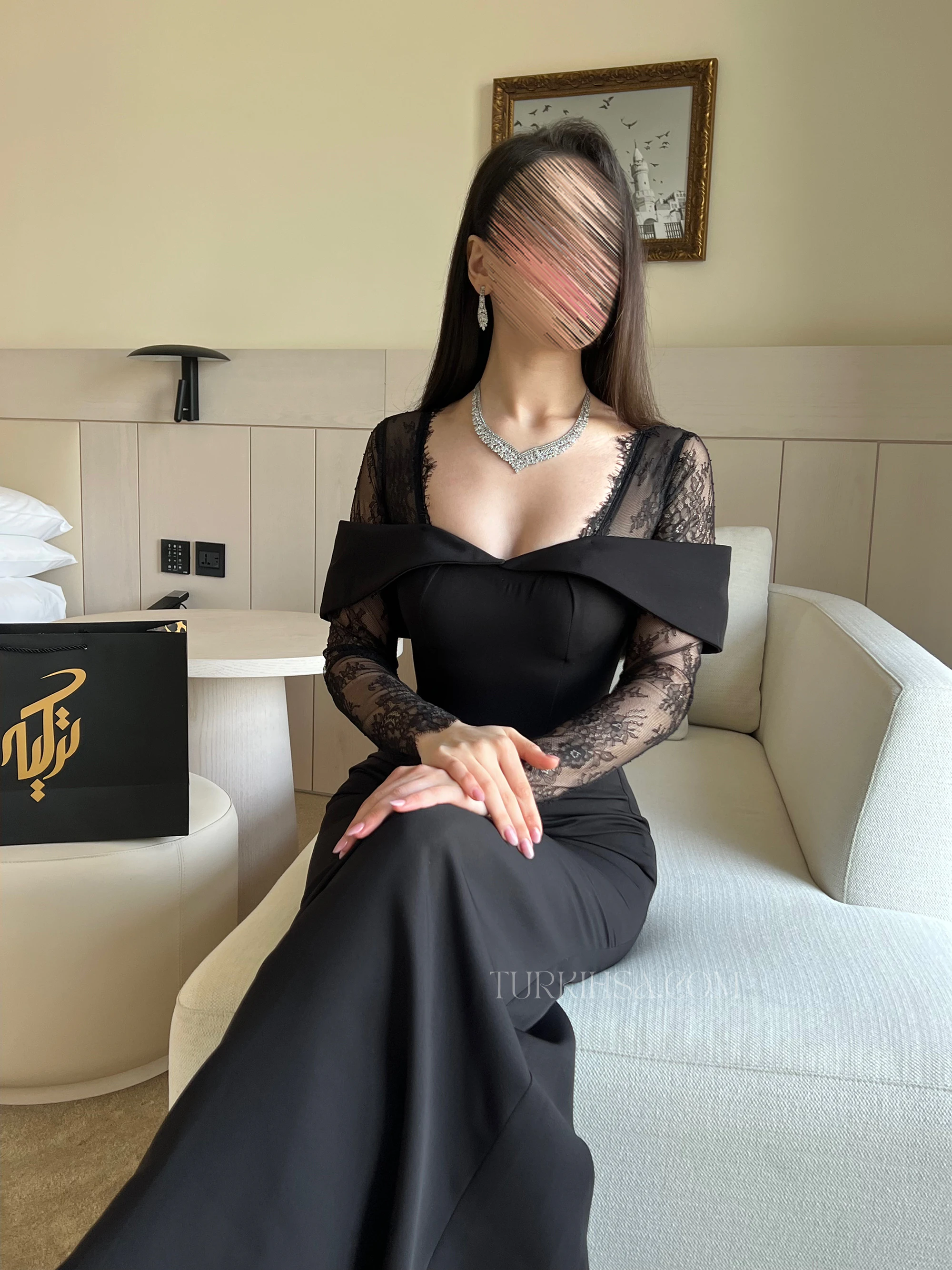 وضعية جلوس تسلط الضوء على تصميم الياقة المرتفعة من الدانتيل والأكمام الطويلة المزينة بنقوش الزهور.