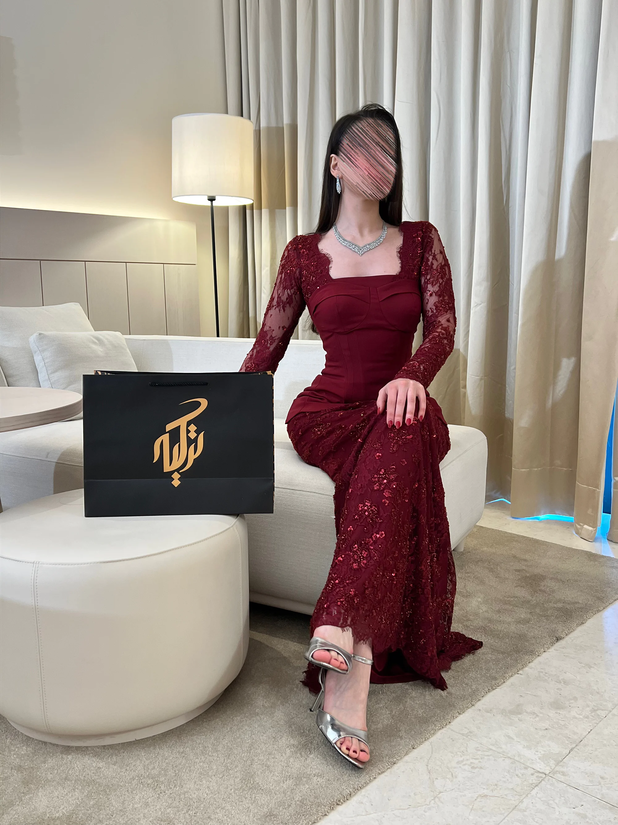 إطلالة بوضعية الجلوس تعكس رقي التصميم وتبرز فخامة اللون البرغندي الغني وتناسقه التام مع تفاصيل الدانتيل المطرز.