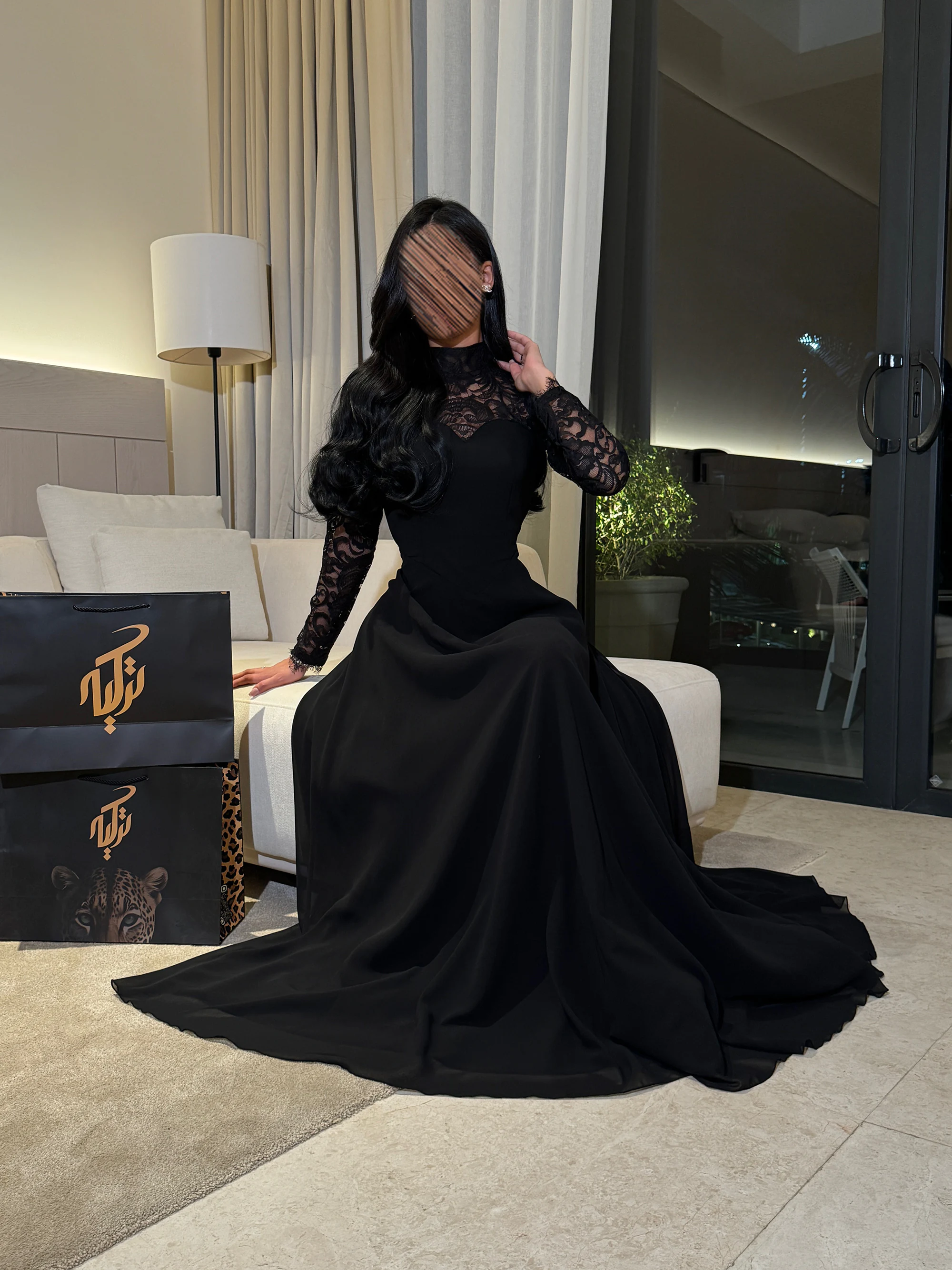 تناغم التصميم الراقي وانسدال التنورة بنعومة، مما يعكس راحة القماش وأناقة أكمام الدانتيل الطويلة في كافة وضعياتك خلال السهرة.