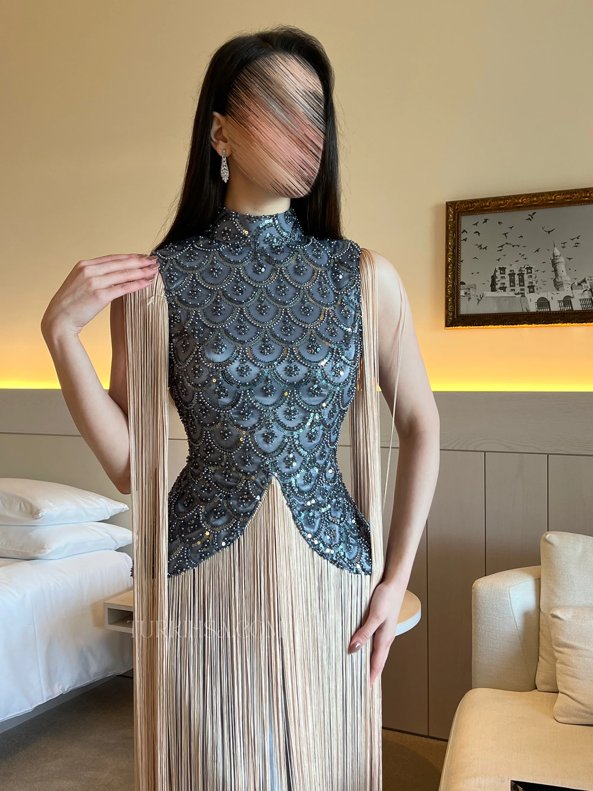 وضح أناقة الياقة العالية (High-neck) وتفاصيل الخرز البراق الذي يغطي قماش التفتة ليعكس رقي الإطلالة.