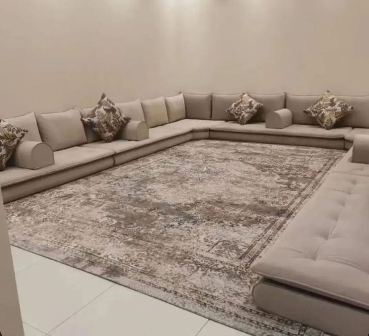 صورة لمجلس عربي مودرن باللون البيج مع وسائد ملونة وسجادة بنقوش يعكس تصميما أنيقا ومريحا 