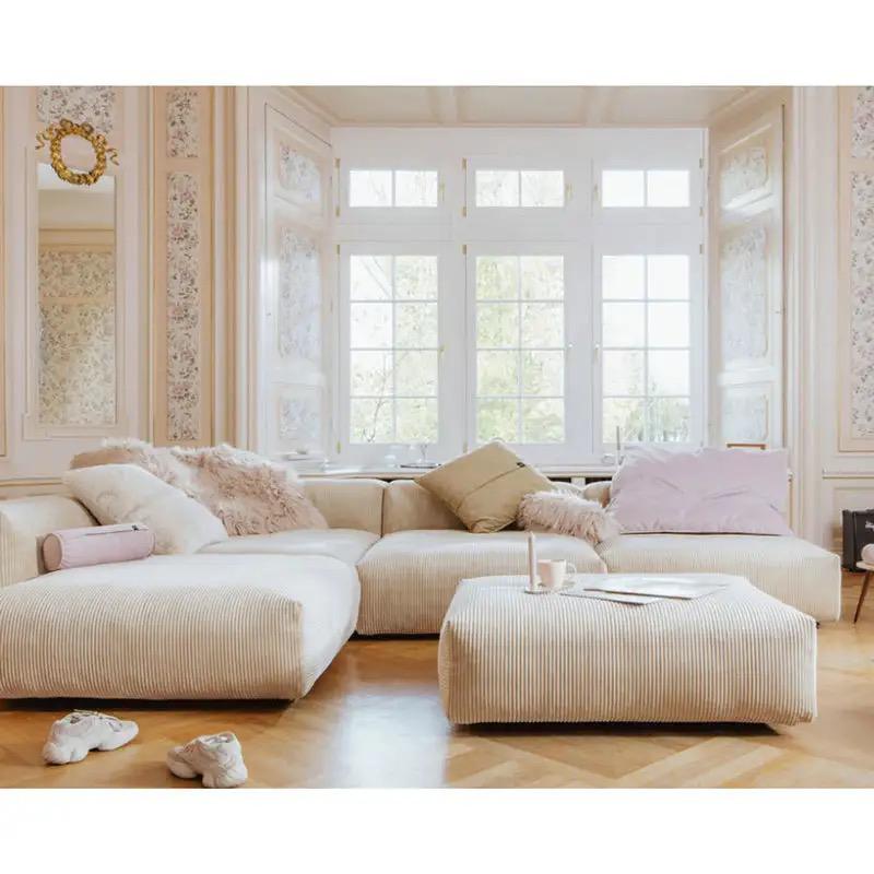 A closeup of a comfortable corner sofa with cushions and a large window in the background