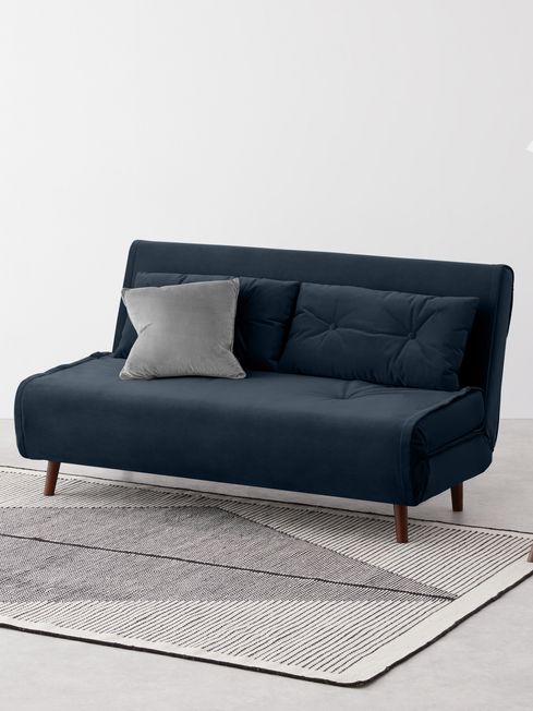 أريكة سرير مخملية زرقاء أنيقة مع وسائد على سجادة بنمط هندسي