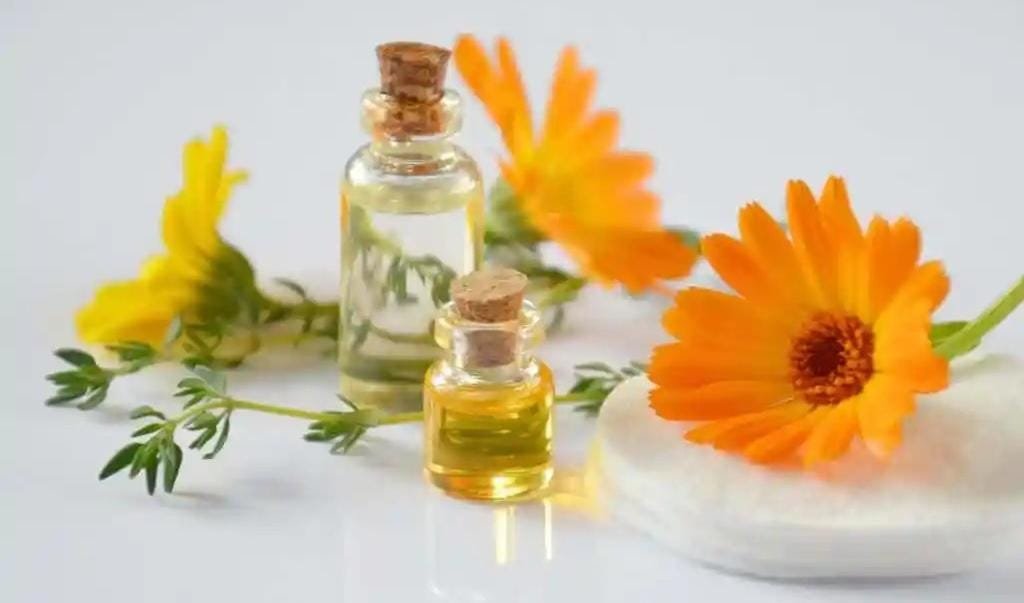 زيت عطري للوجه والجسم زجاجات بأحجام مختلفة مع زهور ملونة وأوراق خضراء