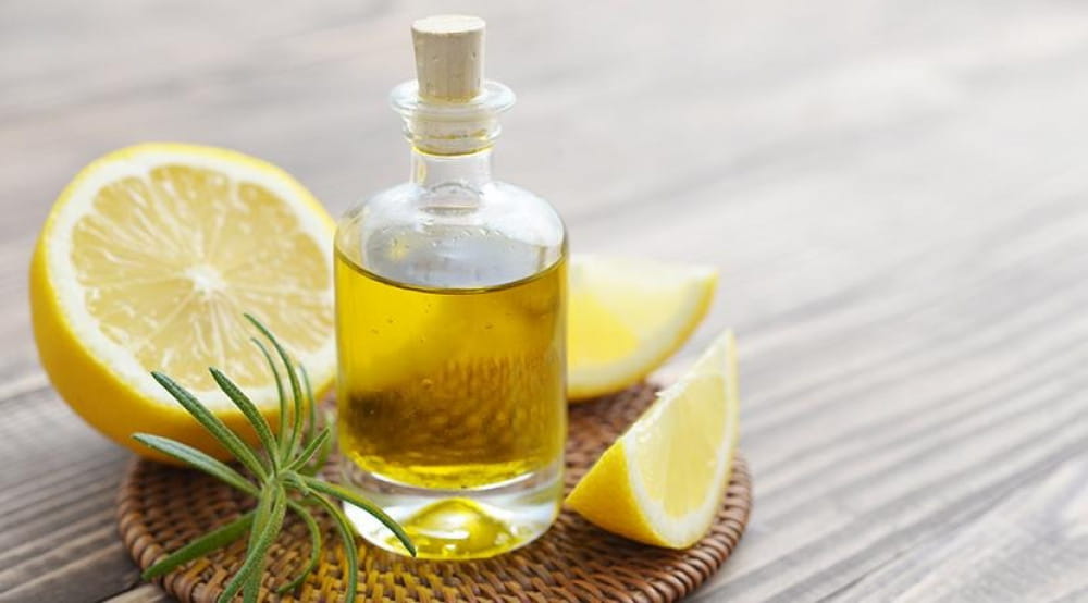 زيت الليمون العطري زيت عطري طبيعي زجاجة زيت مع شرائح ليمون طازجة ونبات أخضر على سطح خشبي