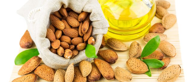 زيت اللوز كيس من اللوز وزيت اللوز على سطح خشبي