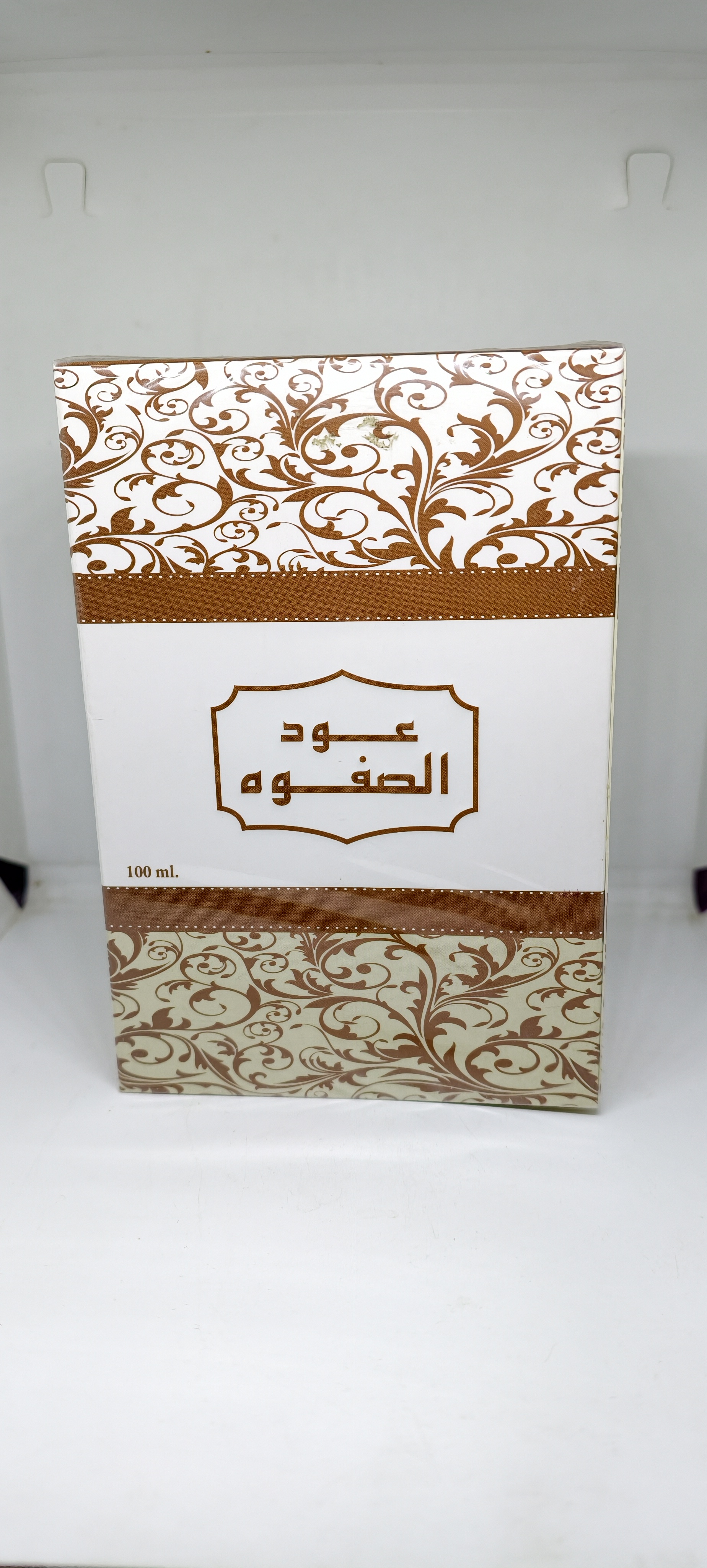 صندوق عطر بخاخ من الجنيد بحجم 100 مل بتصميم زخارف عربية باللون البني على خلفية بيضاء مع كتابة عود الصفوة