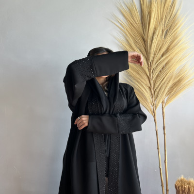 مودل ترتدي عباية سوداء مطرزة ومرصعة بالكريستال على الأكمام وأطراف الأمام بإطلالة فاخرة