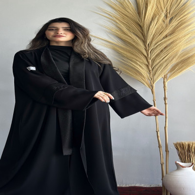 مودل ترتدي عباية سوداء بتصميم بليزر نص كلوش مع تفاصيل مشجرة أنيقة على الياقة والأكمام