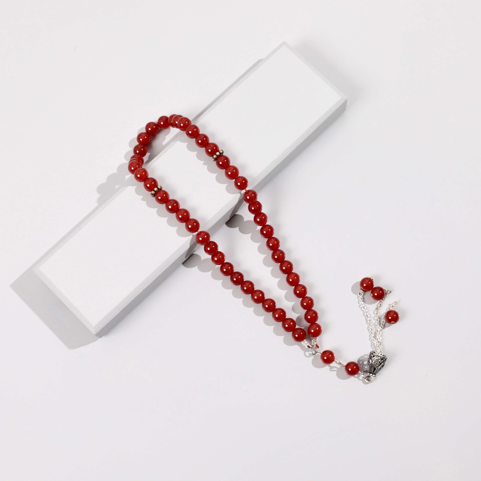 Red prayer beads with a decorated silver tassel by Irth