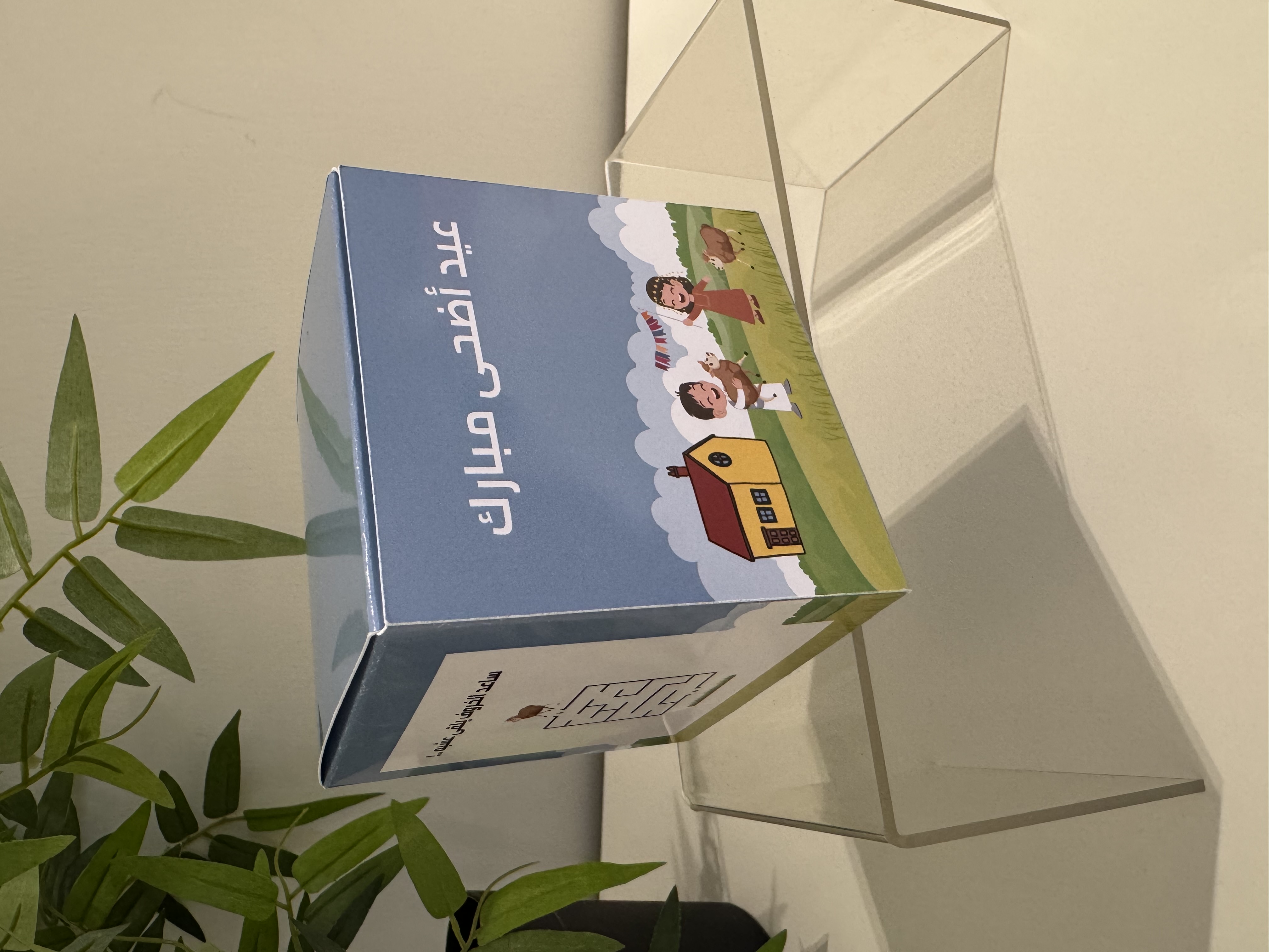 تصميم خارجي يعرض أطفال يحتفلون بجانب خراف ومنزل مع عبارة “عيد أضحى مبارك”