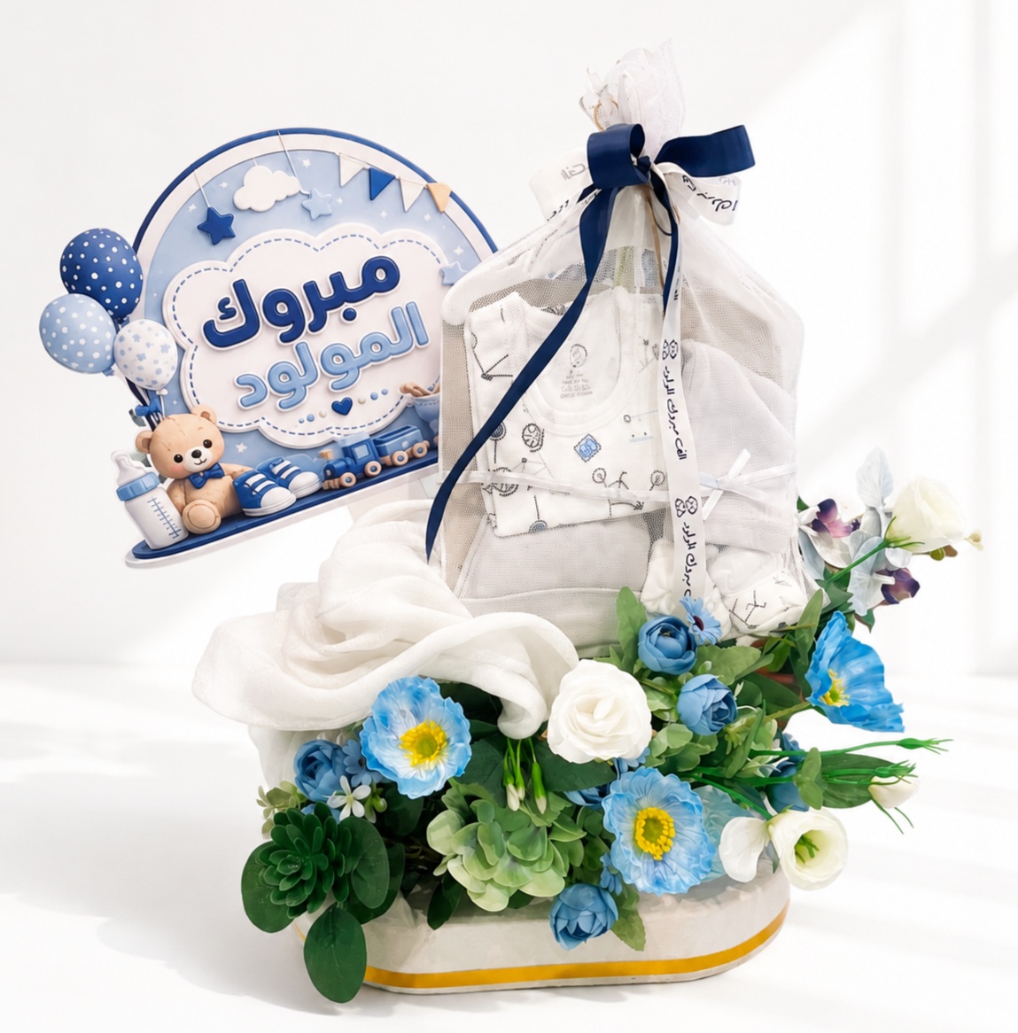 Luxury baby boy gift arrangement with newborn clothes, blue and white flowers, and a congratulatory newborn sign.