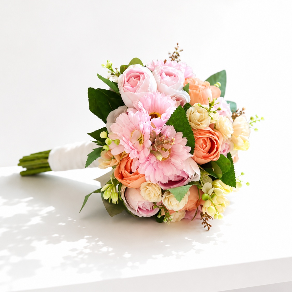 Elegant bridal bouquet featuring blush pink, peach, and ivory flowers with fresh greenery