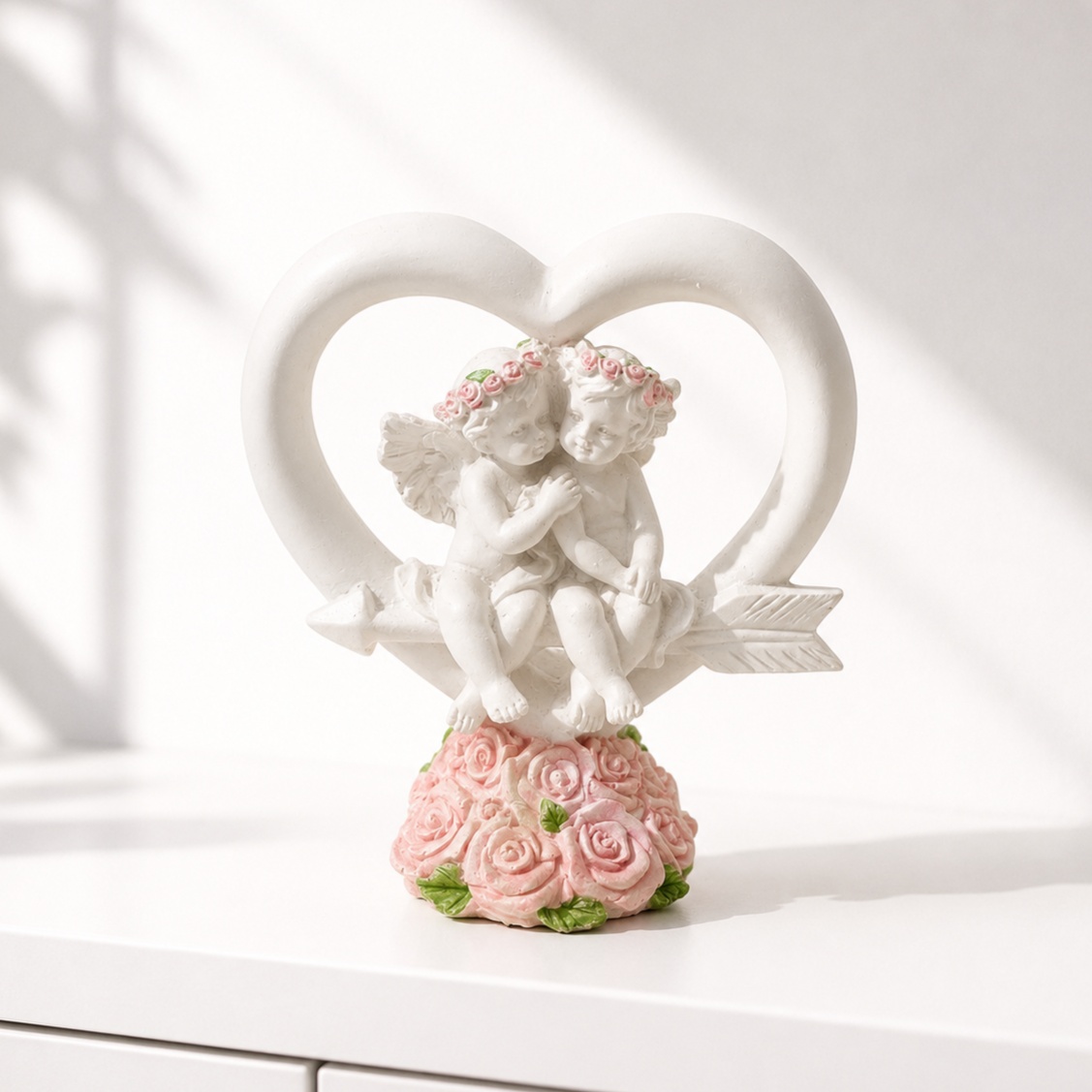 Romantic cherub figurine inside a heart frame with a pink rose base
