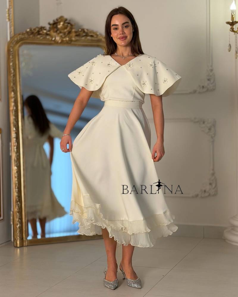 Dress with embroidered cape and pleats at the bottom