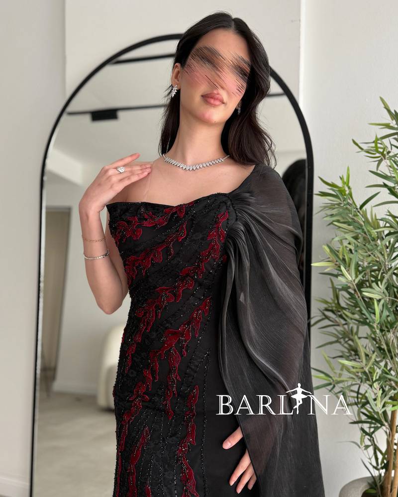 Black dress embroidered with red and with a side cape