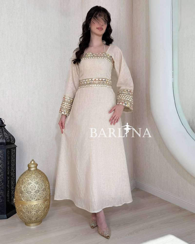 A soft beige jalabiya decorated with gold embroidery