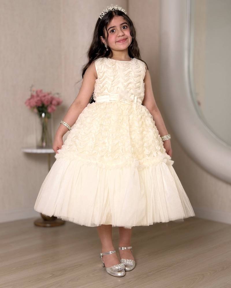 A cream-colored girl's dress adorned with elegant details