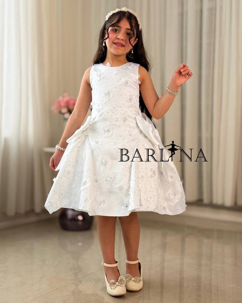 A white, fluffy girl's dress decorated with bows on the sides