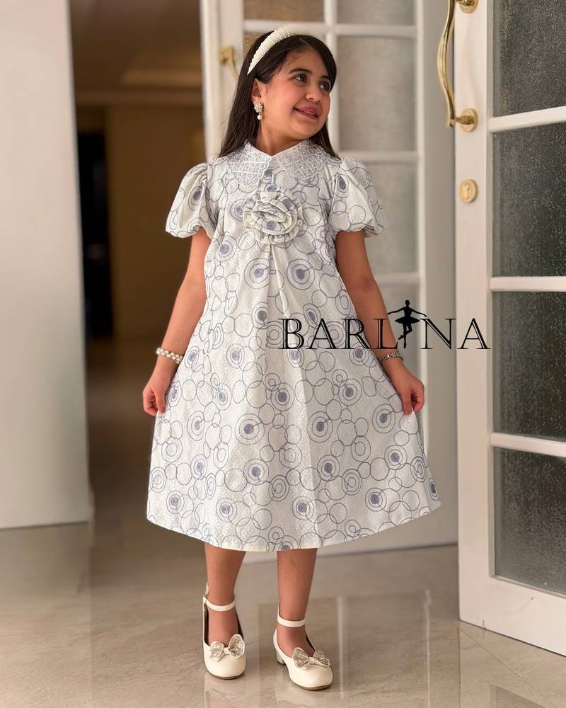 A girl's dress decorated with circle patterns and a raised rose