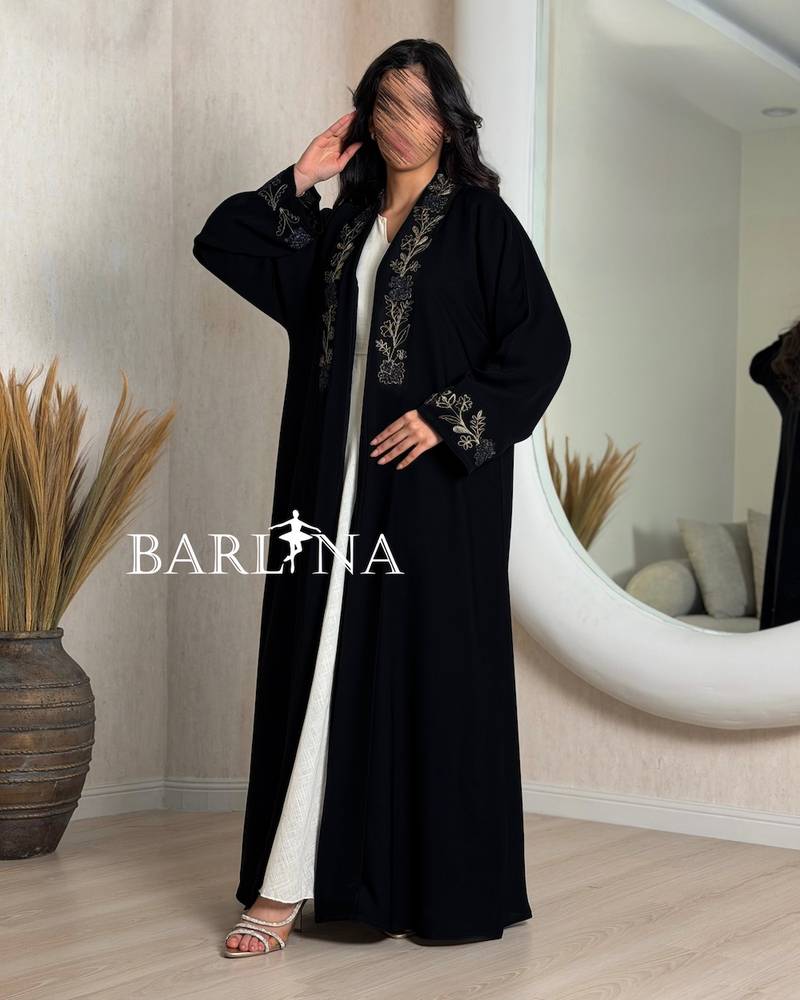 A black abaya decorated with gold embroidery