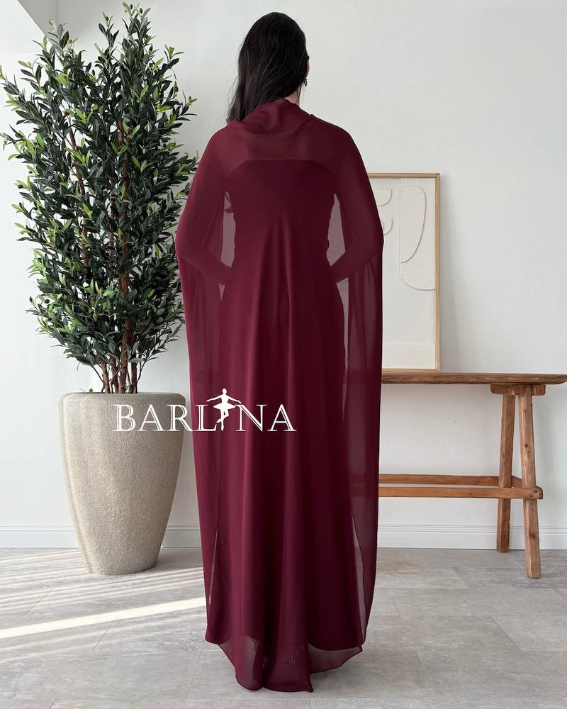 Burgundy dress with a cape draping from the shoulders