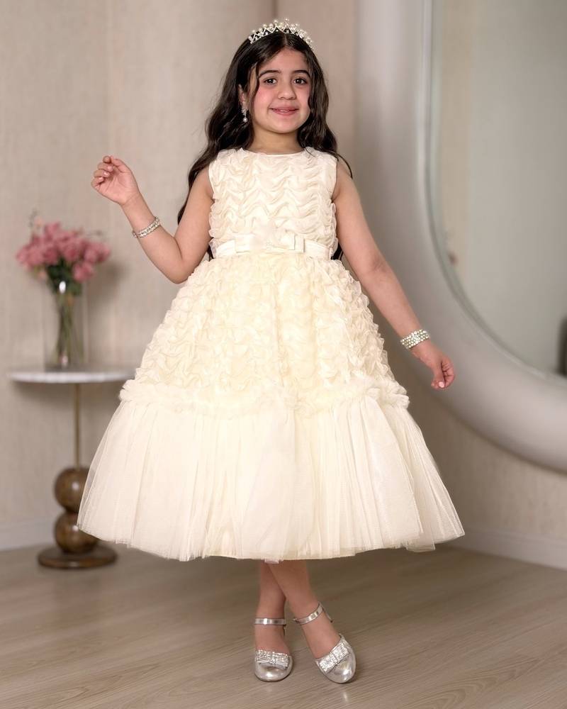A cream-colored girl's dress adorned with elegant details
