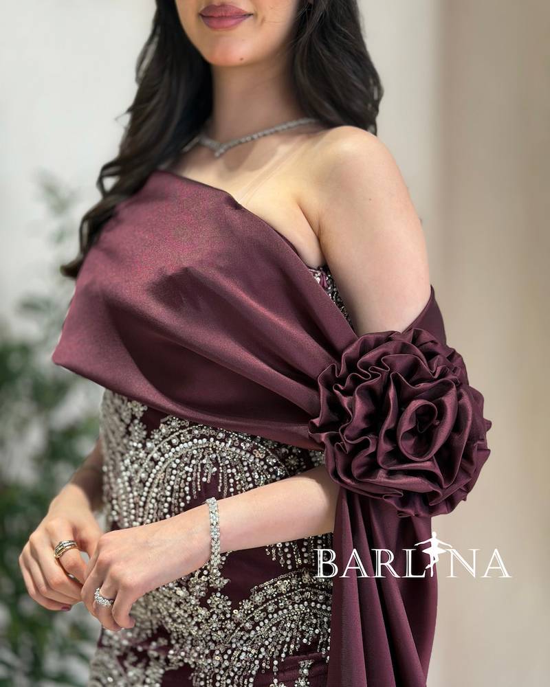 A burgundy dress with silver embroidery and a matching train.
