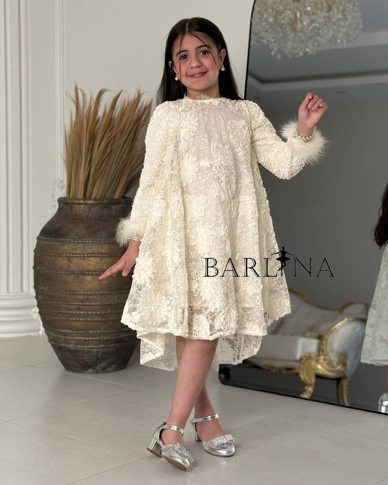 A cream-colored girl's dress with shimmering decorative details.