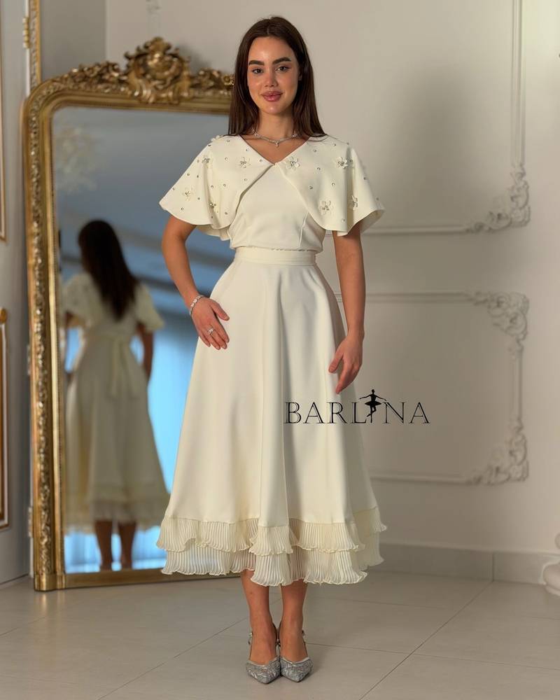 Dress with embroidered cape and pleats at the bottom