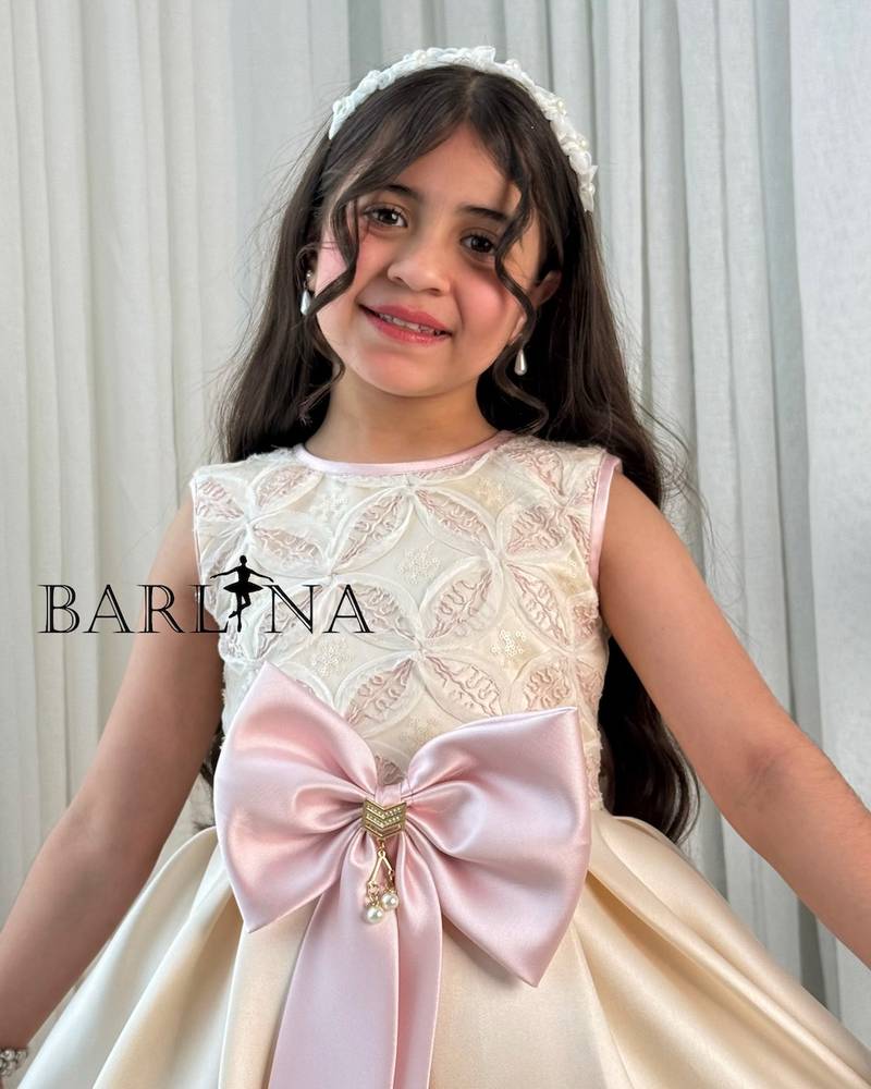 Beige girl's dress decorated with a pink bow