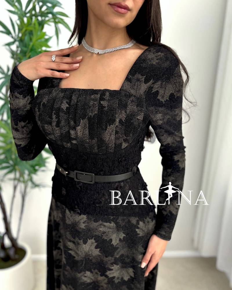 A soft black dress with a subtle pattern and a thin belt
