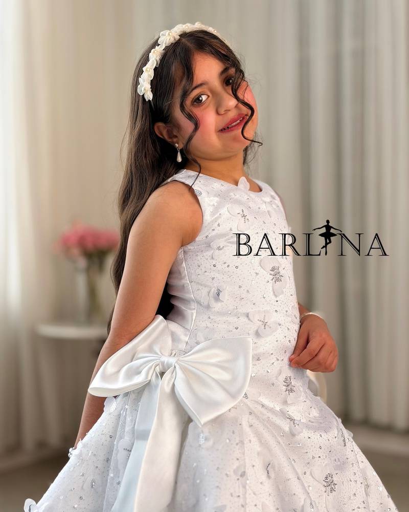 A white, fluffy girl's dress decorated with bows on the sides