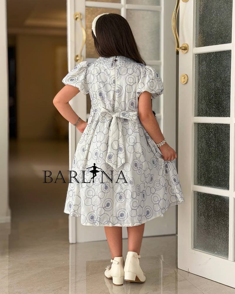 A girl's dress decorated with circle patterns and a raised rose