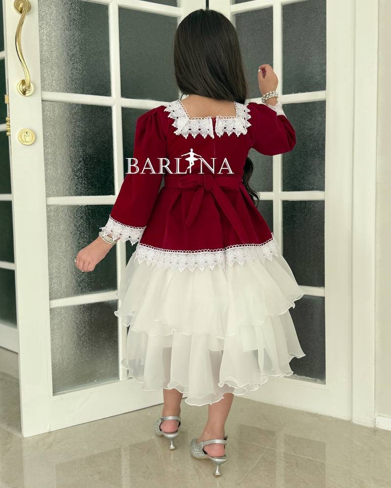 A burgundy girl's dress adorned with classic trim