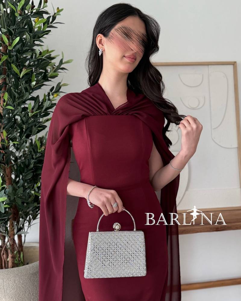 Burgundy dress with a cape draping from the shoulders