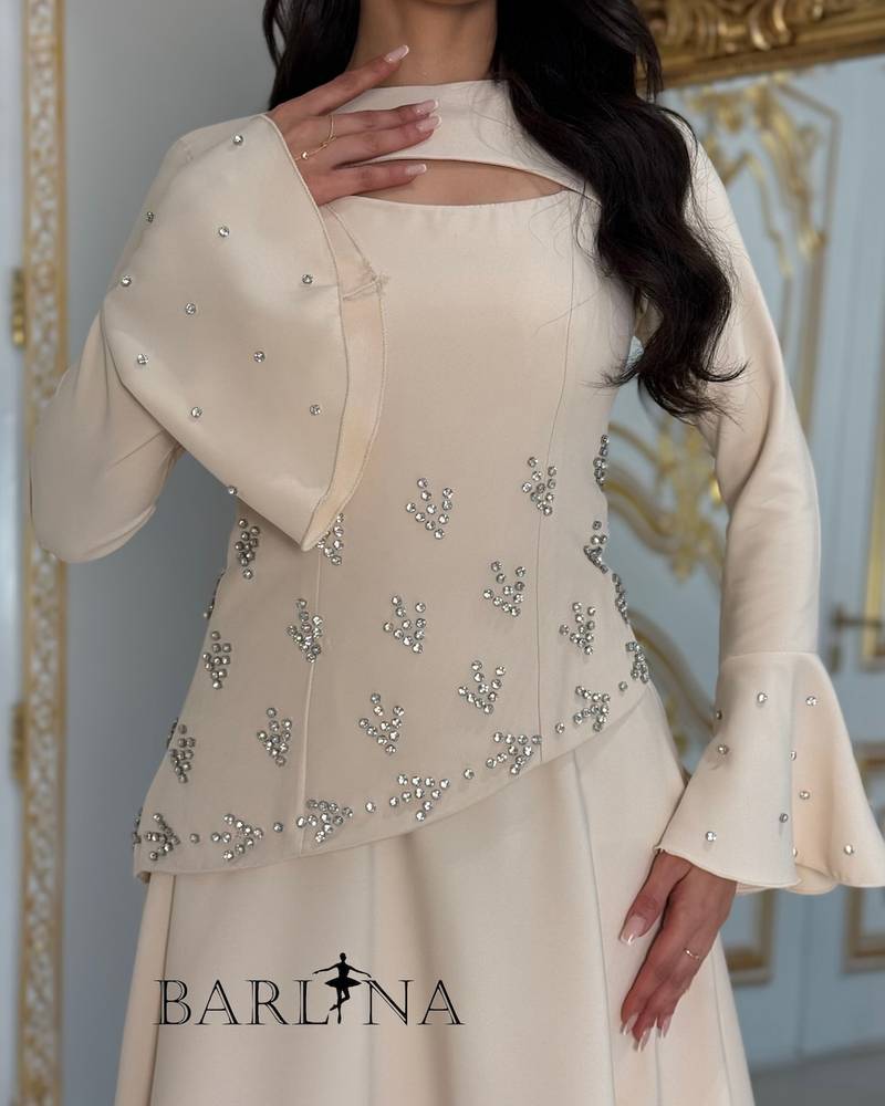 Beige dress adorned with crystals and a piece on the sleeve