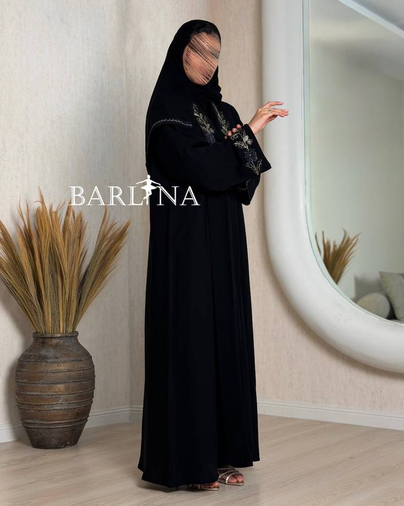 A black abaya decorated with gold embroidery