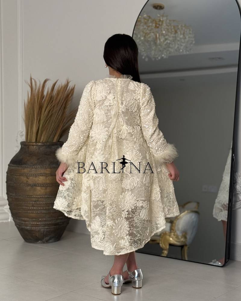 A cream-colored girl's dress with shimmering decorative details.