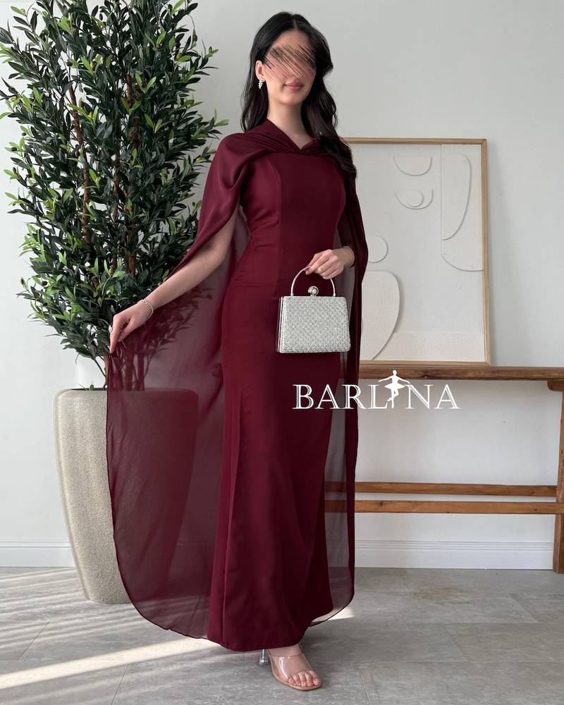 Burgundy dress with a cape draping from the shoulders
