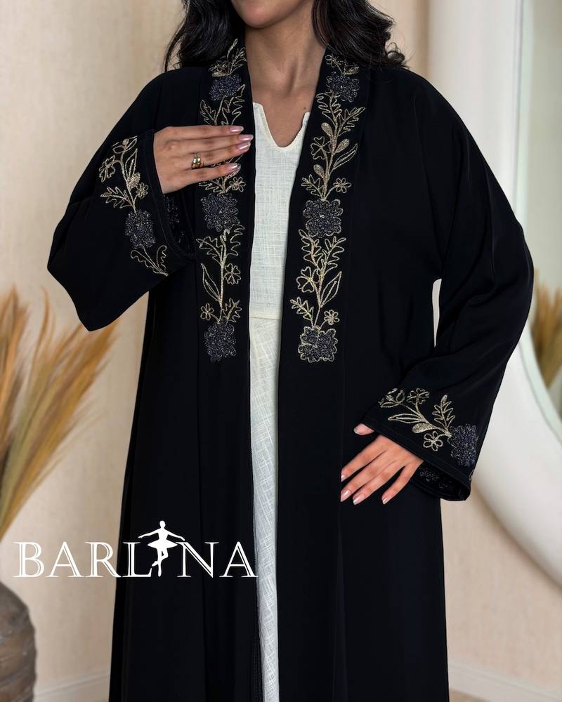 A black abaya decorated with gold embroidery