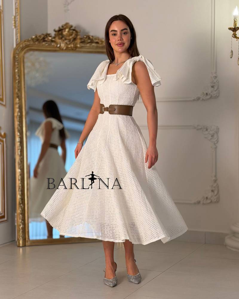 A white dress with soft fabric and ruffled shoulders