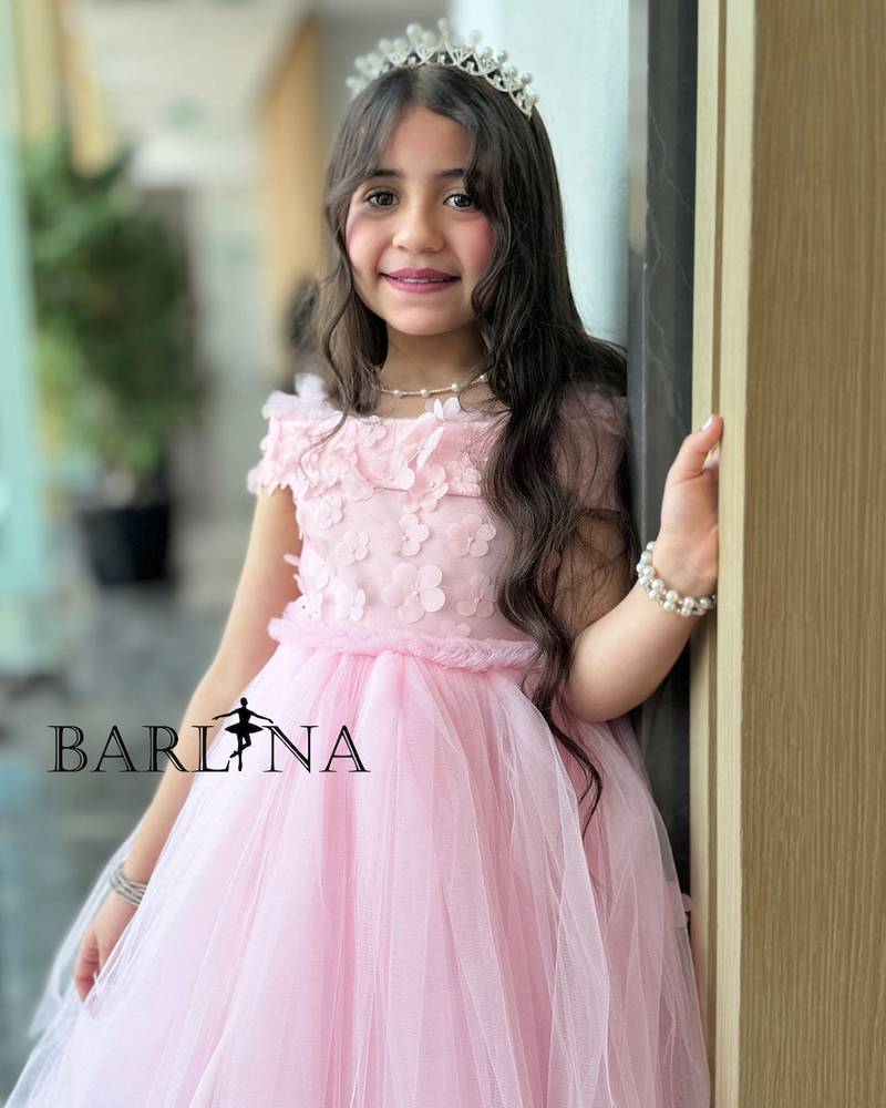 Pink girl's dress decorated with roses on the shoulder
