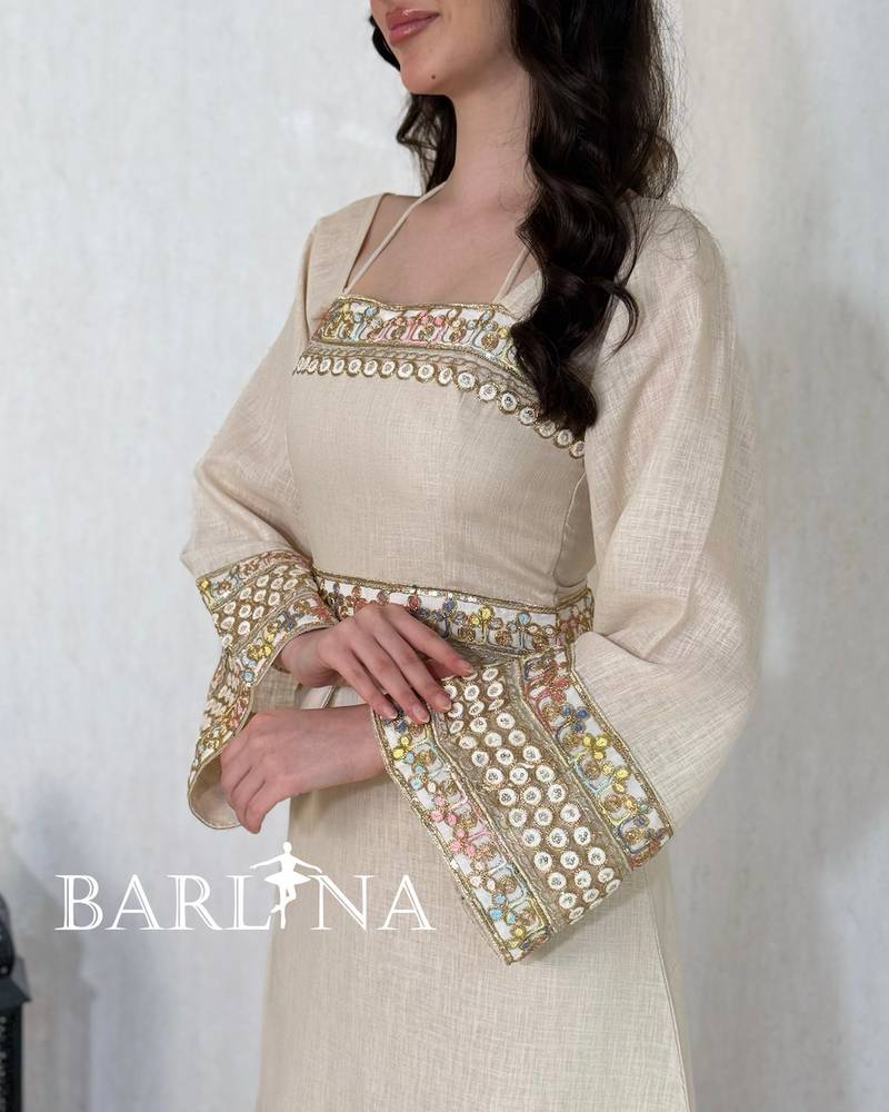A soft beige jalabiya decorated with gold embroidery
