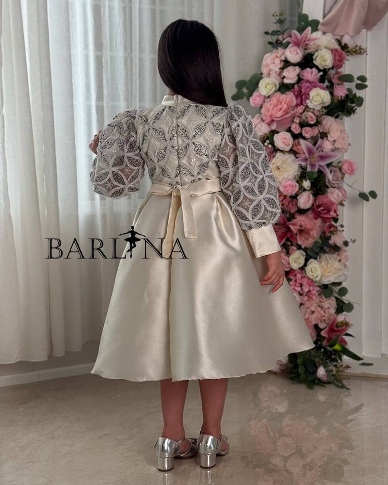A puffy, off-white girl's dress with geometric patterns