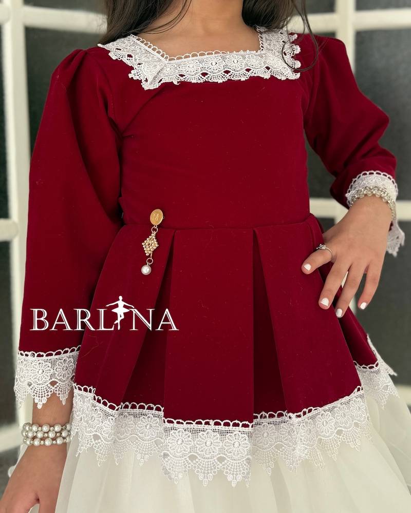 A burgundy girl's dress adorned with classic trim