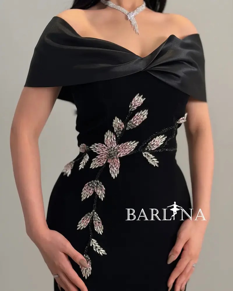 A black dress with a soft cut adorned with shimmering roses.