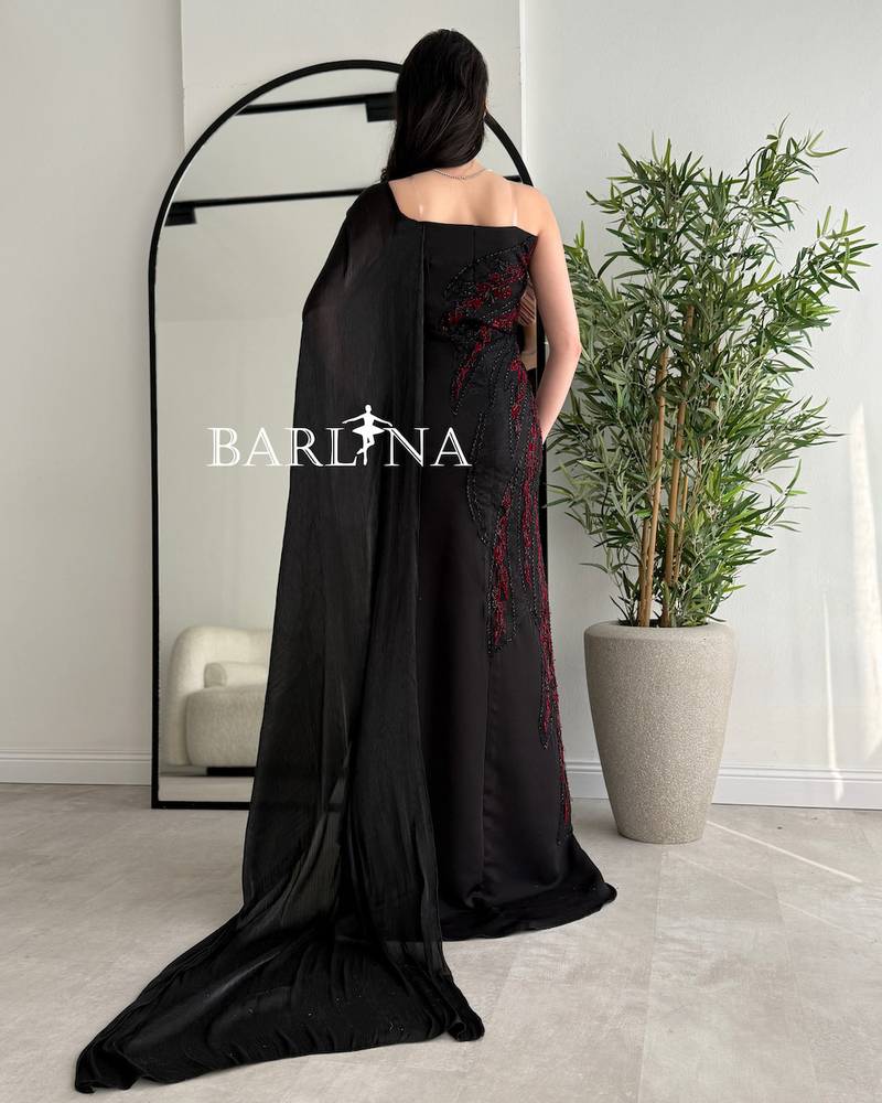 Black dress embroidered with red and with a side cape